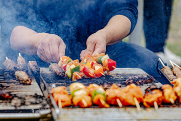 Close-up of a man making Chicken Shish Kebab on Gill