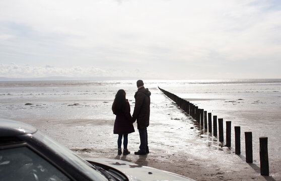 Silhouette couple on wet sunny winter beach