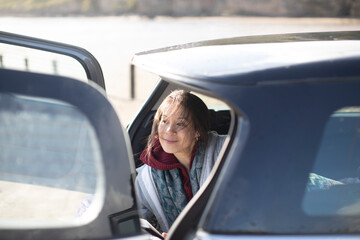 Happy woman relaxing at back of car