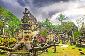 Mystic tropical garden with hindu and buddhist mythological creatures stone sculptures, storm clouds - Buddha Park (Wat Xieng Khuan), Vientiane, Laos