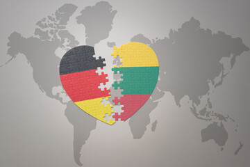 puzzle heart with the national flag of lithuania and germany on a world map background. Concept.