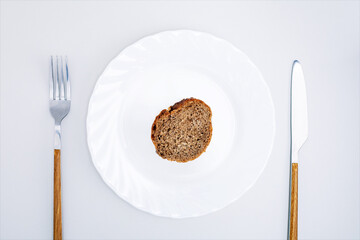 Top view of a piece of black bread on a white plate. Food crisis,