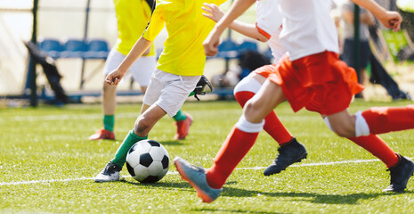 Obraz premium Young Boys Compete in Tournament Match in a Duel. Football Game on Summer Sunny Day. School Kids in Yellow and White and Red Jersey Uniforms Running Classic Soccer Ball on Grass Pitch