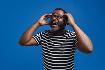 Black man in eyeglasses expressing surprise while holding his head