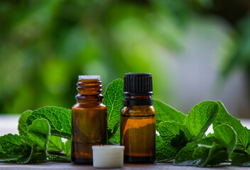 Bottle with essential oil and mint isolated on a light background.