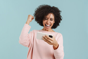 Young black woman gesturing while playing online game on cellphone