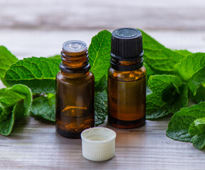 Bottle with essential oil and mint isolated on a light background.