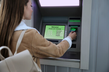 Young woman using cash machine for money withdrawal outdoors