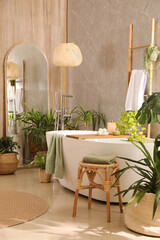 Modern white tub and beautiful green houseplants in bathroom. Interior design