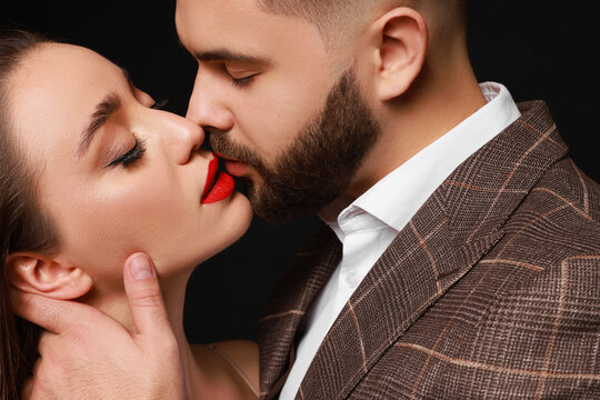 Handsome bearded man with sexy lady on black background, closeup