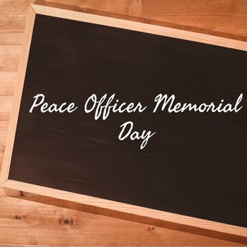 Digital composite image of peace officer memorial day text over writing slate on wooden table