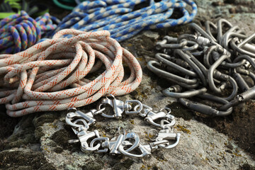 Different ropes and carabiners on rock, closeup. Climbing equipment