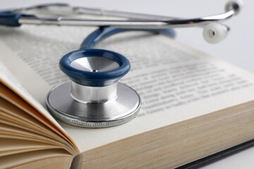 Open student textbook with and stethoscope, closeup. Medical education