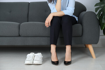 Comfortable sneakers near businesswoman wearing high heel shoes indoors, closeup