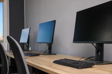 Open office interior. Modern workplaces with computers near light grey wall