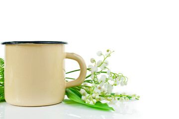 Yellow enamel cup with lily of the valley or may bells flowers isolated on a white background.