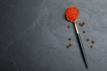 Spoon with delicious red caviar on black table, flat lay. Space for text