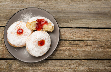 Delicious donuts with jelly and powdered sugar on wooden table, top view. Space for text