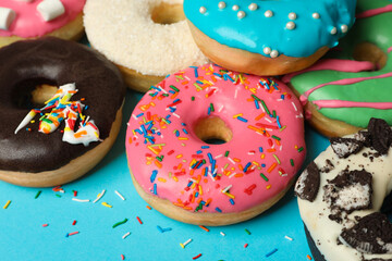 Different delicious glazed doughnuts on light blue background, closeup