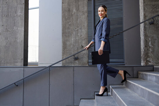 Portrait of elegant business woman in a suit walking down the stairs