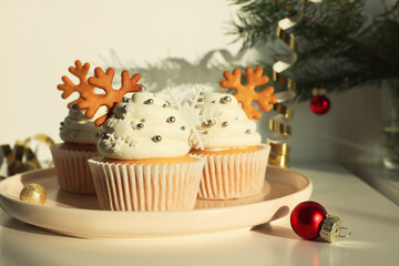 Tasty Christmas cupcakes with cream and snowflake cookies on white table