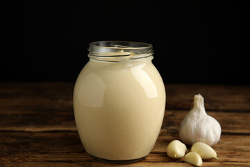 Jar of delicious mayonnaise and fresh garlic on wooden table