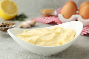 Delicious homemade mayonnaise near ingredients on grey table, closeup