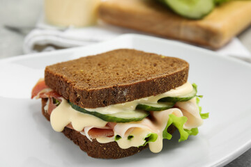 Delicious sandwich with vegetables, ham and mayonnaise on grey table, closeup