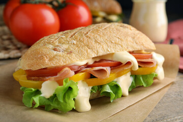 Delicious sandwich with vegetables, ham and mayonnaise served on wooden table, closeup