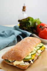 Delicious sandwich with vegetables, ham and mayonnaise on parchment paper, closeup