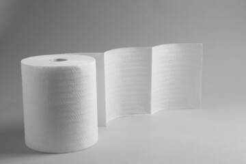 Roll of white paper towels on grey background. Space for text