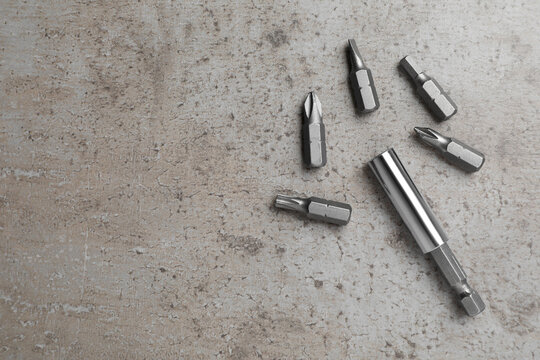 Different drill bits on grey table, flat lay. Space for text