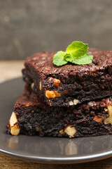 Delicious brownies with nuts and mint on grey plate, closeup