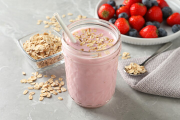 Jar of tasty berry oatmeal smoothie on grey table