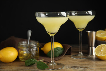 Delicious bee's knees cocktails and ingredients on wooden table against dark background