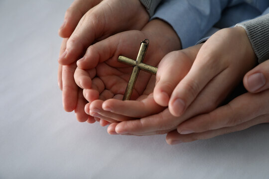 Boy and his godparents holding cross on white background, closeup
