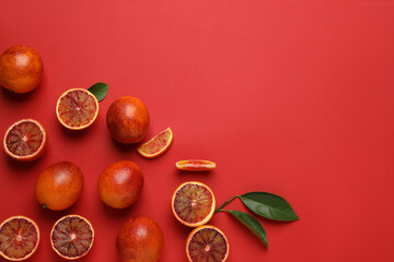 Many ripe sicilian oranges and leaves on red background, flat lay. Space for text