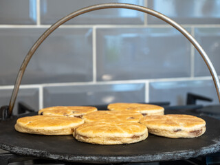 selected focus Welsh Cakes cooking on a cast iron griddle over a gas hob flame