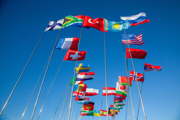 National flags of countries against a clear blue sky with copy space