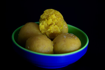 yellow laddoo isolate on black background,front view