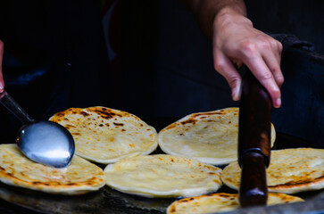 Man baking roti on the fried oil. Parathas are being baked in big dish