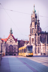 A yellow tram runs over a bridge in the city center of Dresden.