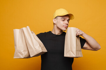 Young delivery man wearing cap posing with paper bags - Powered by Adobe
