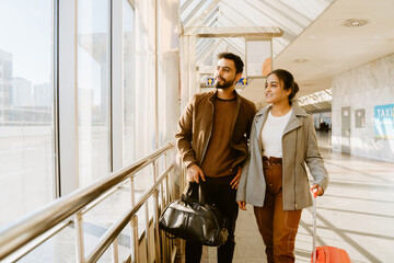 Young indian couple looking in window together at airport