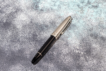 Fountain pen on a marble and gray background. Selective focus.