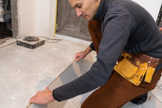 Repairman laying laminate flooring at home.