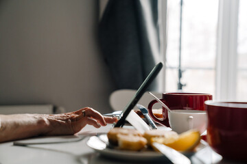 Fototapeta na wymiar White mature woman using tablet computer while having breakfast