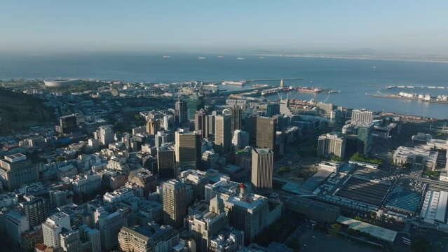 Aerial panoramic footage of city and naval harbour in sea bay. Tall office buildings in city centre. Cape Town, South Africa