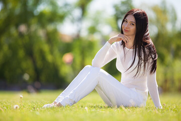 Young woman relax in the park on green grass. Beauty nature scene with colorful background, trees at summer season. Outdoor lifestyle. Happy smiling woman sitting on green grass - 506665814