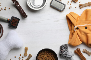 Flat lay composition with dog clothes, food and accessories on white wooden table. Space for text